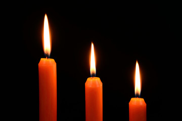 Three orange candles on a black background