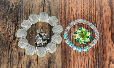 stylish bracelets broach and ring on vintage wood background