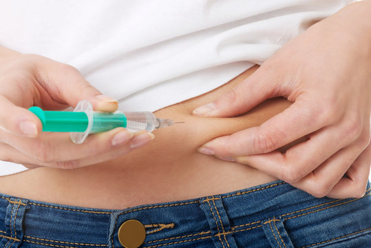 Close up on woman injecting her belly