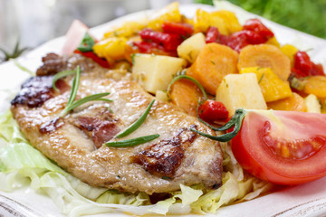 Joint of pork with baked potatoes and fresh vegetables
