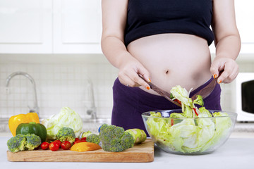 Pregnant mother cooking salad