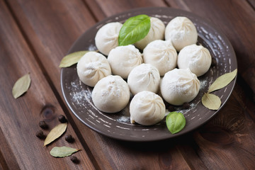 Raw khinkali with herbs and spices on a plate, horizontal shot