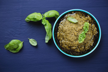 Pesto sauce in a saucer, dark blue wooden surface, above view