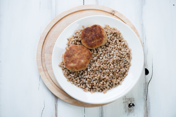 Buckwheat with cutlets on a plate, above view, studio shot