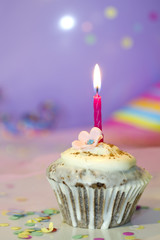 Birthday cupcake closeup on colorful background with candle