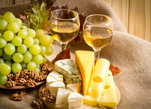 White wine with cheese, walnuts and grapes on sackcloth