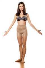 young woman in nylon stockings and bra on a white background