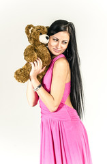 Young brunette in a long pink dress with Teddy