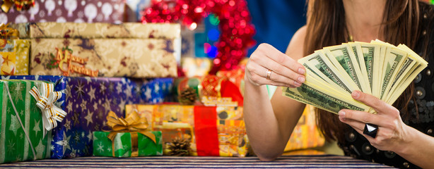 woman counting money at holiday gifts background