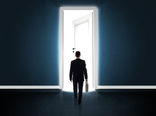 Obraz premium Business man looking at big bright opened door