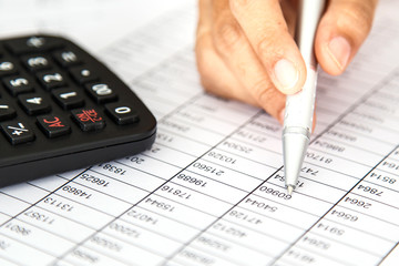 Close up woman hand holding pen on spreadsheet