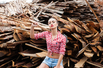 woman ax in hand in a plaid shirt sitting on wooden boards
