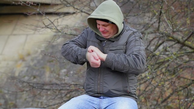 Man with itchy arm at outdoors on the bench