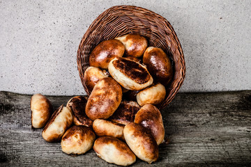 pies with meat or cabbage in a wicker basket on a wooden backgro