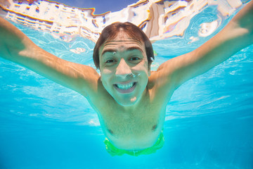 Close up view of smiling man swimming underwater