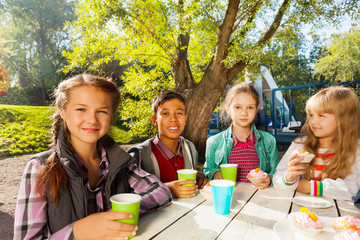 International children drink tea from cups outside