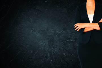 Close up of businesswoman with arms crossed against dark texture