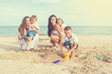 Two young mothers and their children having fun on the beach