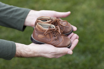 Dirty hands holding a pair of old childrens shoes 