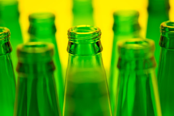 Ten Green Empty Beer Bottles Shot with Yellow Light.
