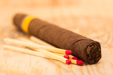 One Cigar and Five Matches with Red Heads on a Wooden Surface