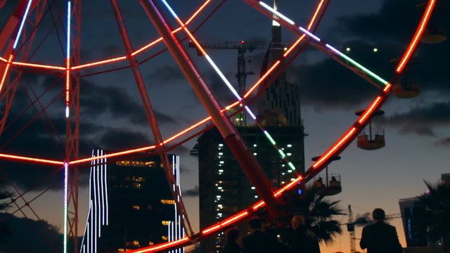 Ferris wheel rotates in the middle of the city at night