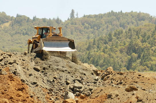 Large bulldozer moving rock in a hill removal
