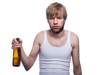 Young man with hangover holding beer bottle. After party