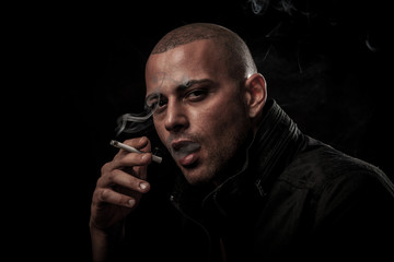 Handsome young man smokes cigarette in darkness - photography of