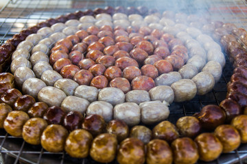 Sausage small circles on the grid-iron grill with smoke over