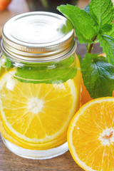 Mug delicious refreshing drink of orange fruit with mint on wood