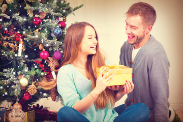 Happy Couple with Christmas Gift at Home. Christmas Celebration