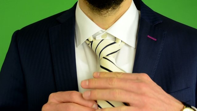 business man adjusts his tie - green screen - studio - closeup