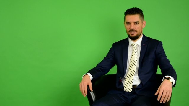 business man sits and talks to camera (interview) - green screen