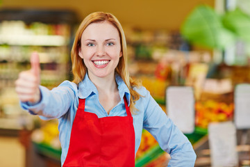 Verkäuferin im Supermarkt hält Daumen hoch