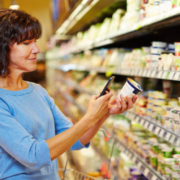 Frau mit Smartphone scannt Barcode im Supermarkt