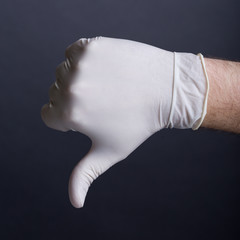 Male hand in latex glove (thumb down sign)