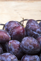plums in a basket on a wooden background