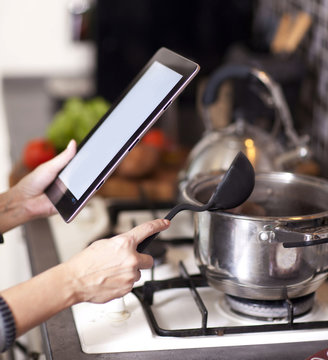 cooking, technology and home concept -a woman, a housewife in th
