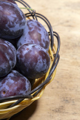 plums in a basket on a wooden background
