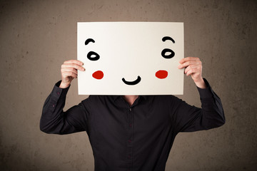 Businessman holding a cardboard with a smiley face on it