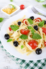 Spaghetti with tomatoes, olives and basil leaves