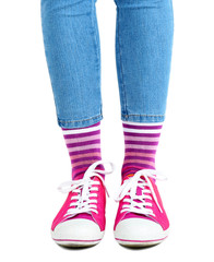 Female legs in colorful socks and sneakers isolated on white