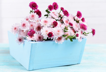 Beautiful flowers in box on table on light background