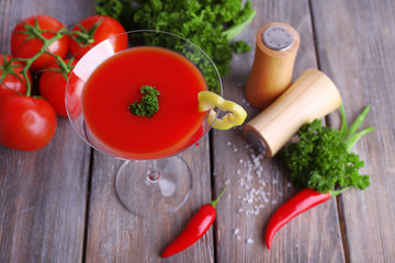 Tomato juice in goblet and fresh vegetables on wooden