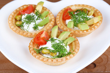 Tartlets with greens and vegetables with sauce on plate on