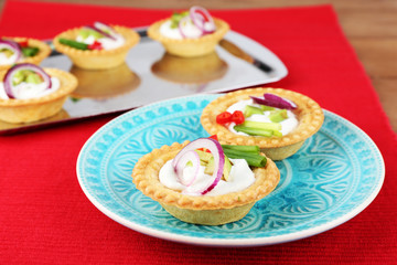Tartlets with greens and vegetables with sauce on plate and
