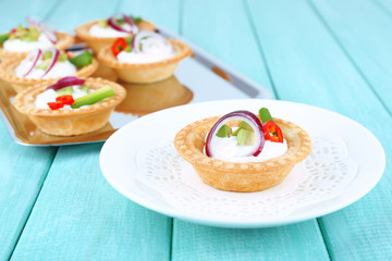 Tartlets with greens and vegetables with sauce on plate and
