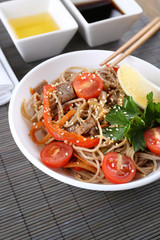 Chinese noodles with vegetables and roasted meat in bowl