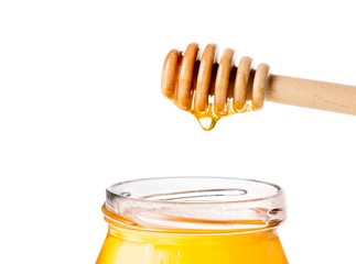 honey jar on white background with wooden honey dipper on top
